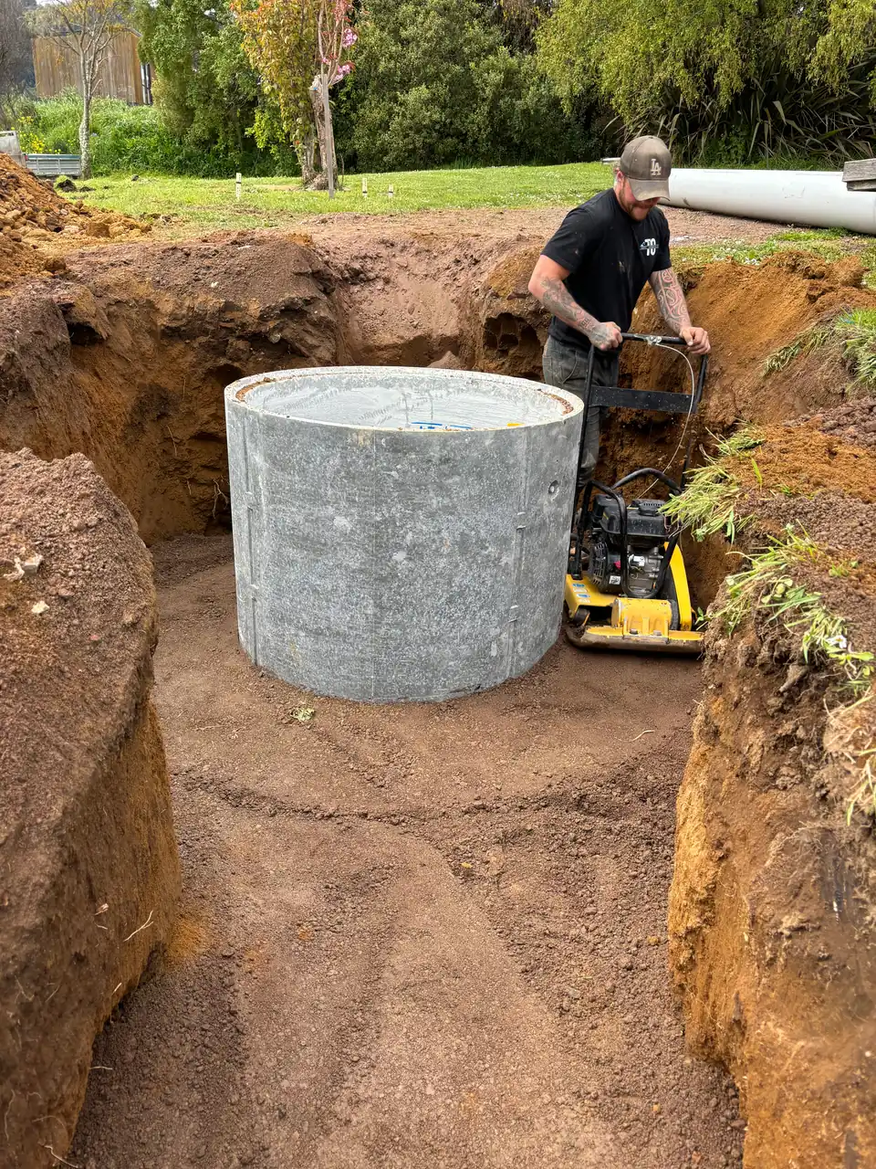 Concrete chamber set in a trench with a plate compactor